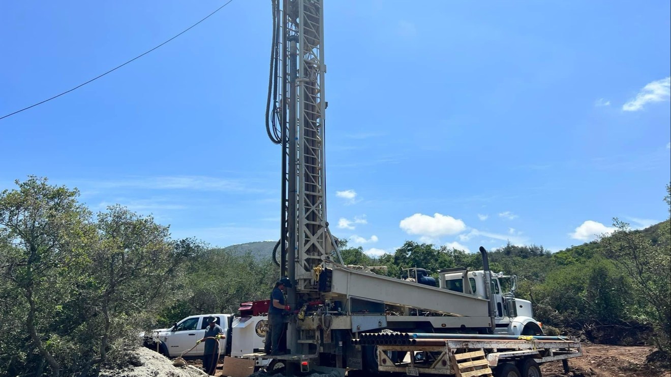 Well drilling rig operating on hillside job site in San Diego County